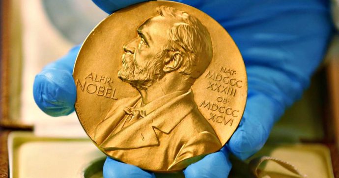 Fotografia di un Premio Nobel tenuto da una mano bardata con un guanto il lattice
